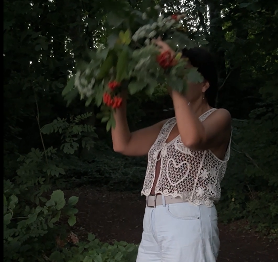 Frau hält einen Strauß roter Blumen im Garten, lässige Sommerbekleidung mit Häkel-Top